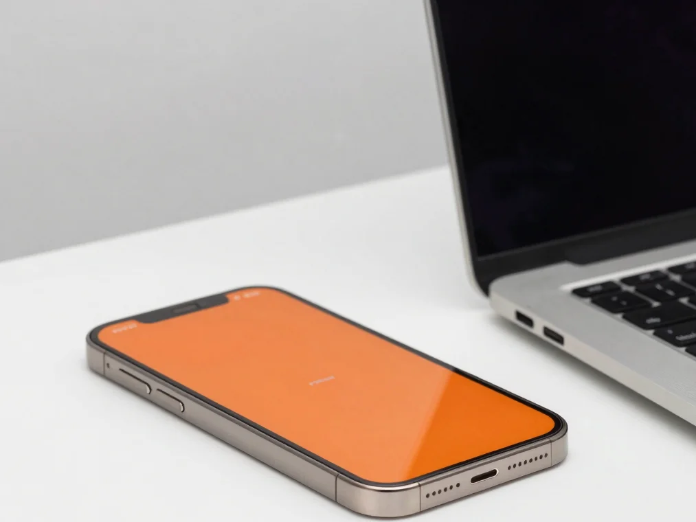 Close-up of a modern smartphone on a clean white desk next to a l